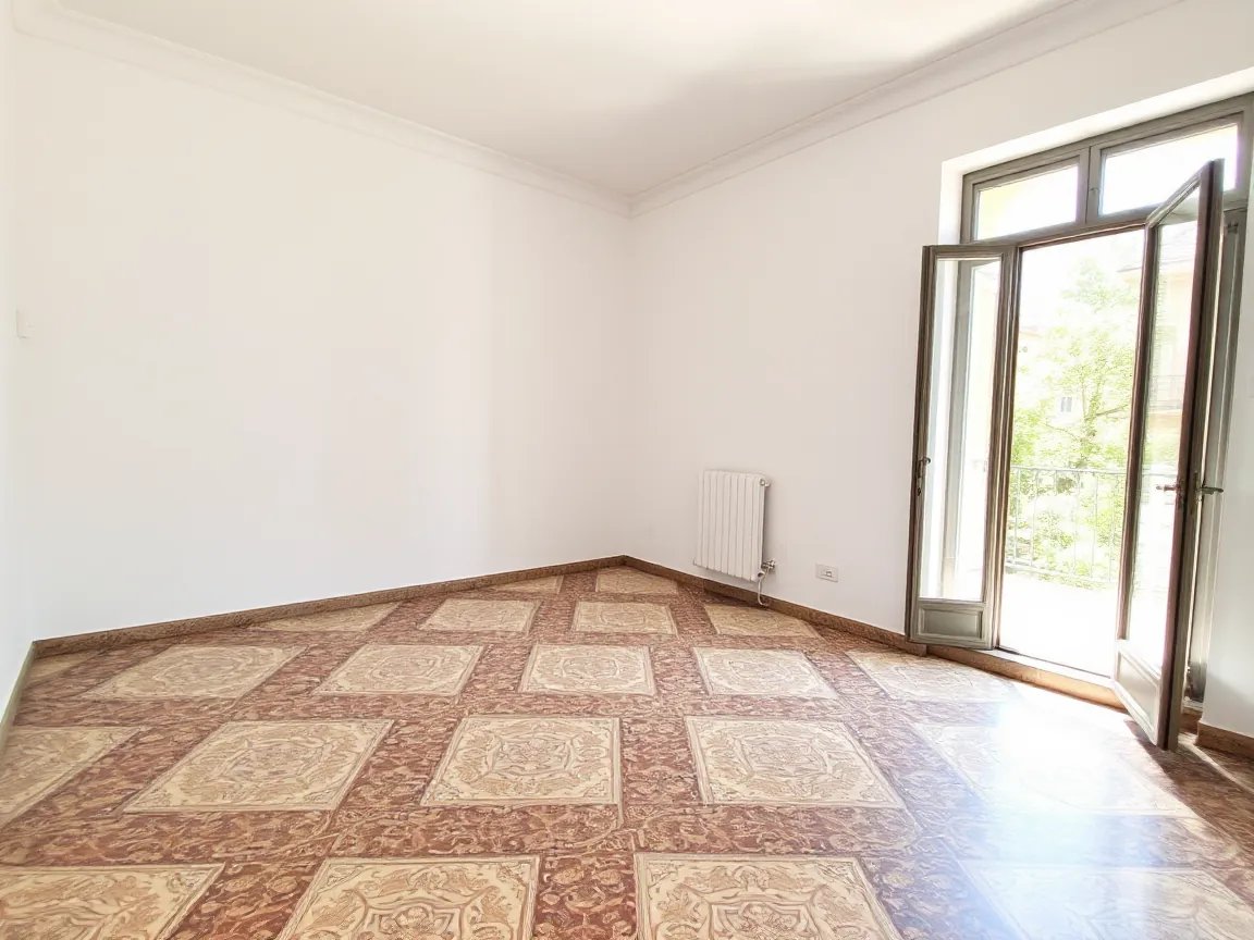 Salón vacío con suelo hidráulico y el balcón abierto.